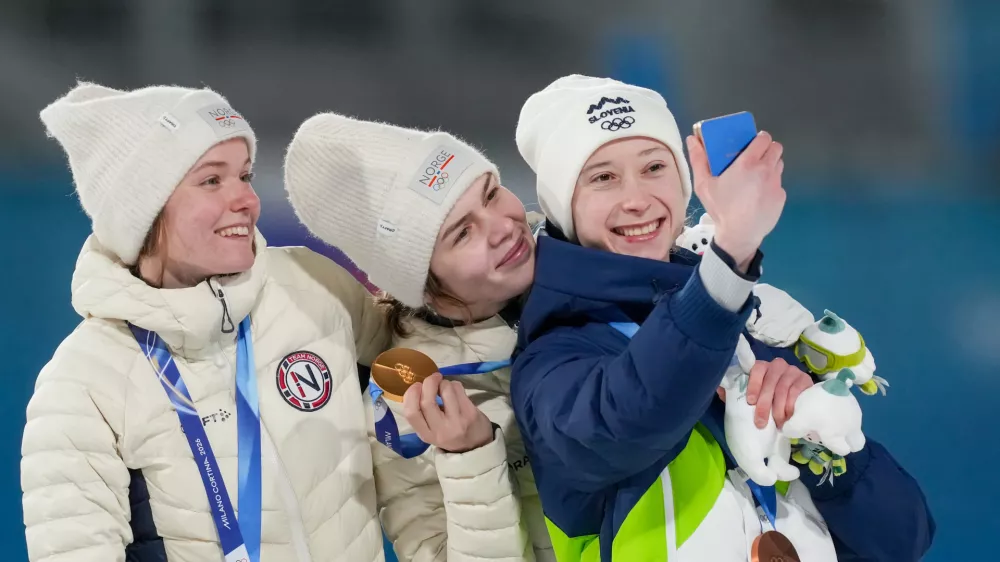 Gold medalist Anna Odine Stroem, of Norway, celebrates on the podium flanked by silver medalist Eirin Maria Kvandal, also of Norway, and bronze medalist Nika Prevc, of Slovenia, right, after the ski jumping women's large hill individual at the 2026 Winter Olympics, in Predazzo, Italy, Sunday, Feb. 15, 2026. (AP Photo/Evgeniy Maloletka)