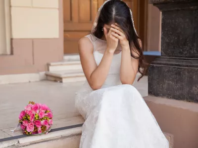 Hopeless bride crying outside a church after being stood up on her wedding day