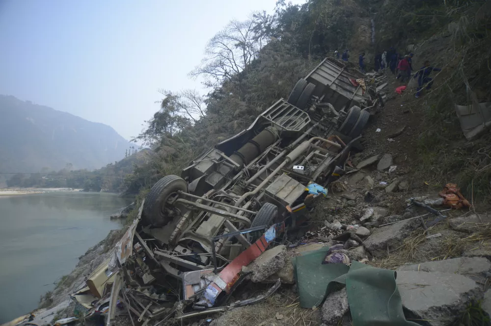 The wreckage of a bus is seen on the bank of the Trishuli River after it drove off a mountain highway near Benighat, west of the capital, Kathmandu, Nepal, Monday, Feb. 23, 2026. (AP Photo/Bijay Rai)