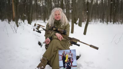 Tetiana Khimion 47, now a sniper in the Ukrainian army, poses with a photograph of herself as a dance teacher taken before Russia's full-scale invasion, in a park in Kyiv, Ukraine, Sunday, Feb. 22, 2026. (AP Photo/Sergei Grits)