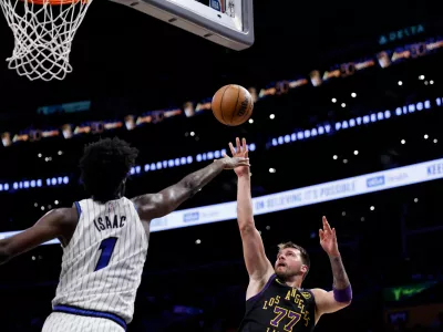 Los Angeles Lakers guard Luka Doncic (77) shoots the ball while being guarded by Orlando Magic forward Jonathan Isaac (1) during the second half of an NBA basketball game Tuesday, Feb. 24, 2026, in Los Angeles. (AP Photo/Caroline Brehman)