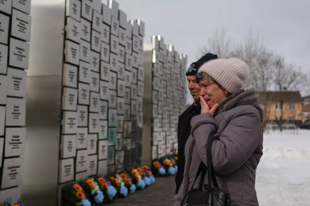 Relatives of those killed during the Russian occupation react at the Wall of Remembrance during a ceremony to mark the fourth anniversary of the Russian invasion of Ukraine, in Bucha, Ukraine, Tuesday, Feb. 24, 2026. (AP Photo/Sergei Grits)