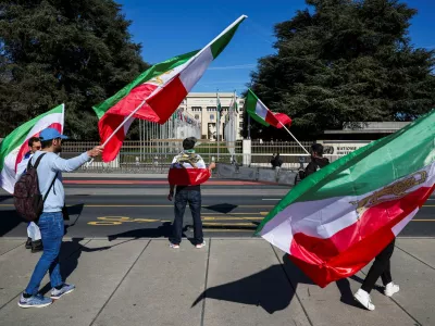 Demonstrators hold the "Lion and Sun" pre-Iranian Revolution national flags during a protest against Iran's government in front of the United Nations Office at Geneva, on the day of a new round of indirect U.S.-Iran talks over their long-running nuclear dispute, in Geneva, Switzerland, February 26, 2026. REUTERS/Pierre Albouy