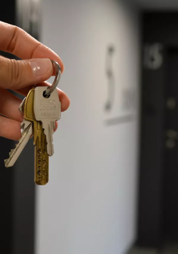 A set of flat keys is shown with a front door in the background, representing a home bought on credit. The image highlights the significance of home security and property access in the context of credit-financed real estate. / Foto: Tannysolt
