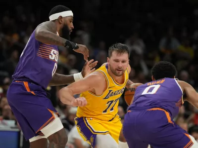 Los Angeles Lakers guard Luka Doncic drives between Phoenix Suns forward Royce O'Neale and forward Ryan Dunn (0) during the second half of an NBA basketball game, Thursday, Feb. 26, 2026, in Phoenix. (AP Photo/Rick Scuteri)