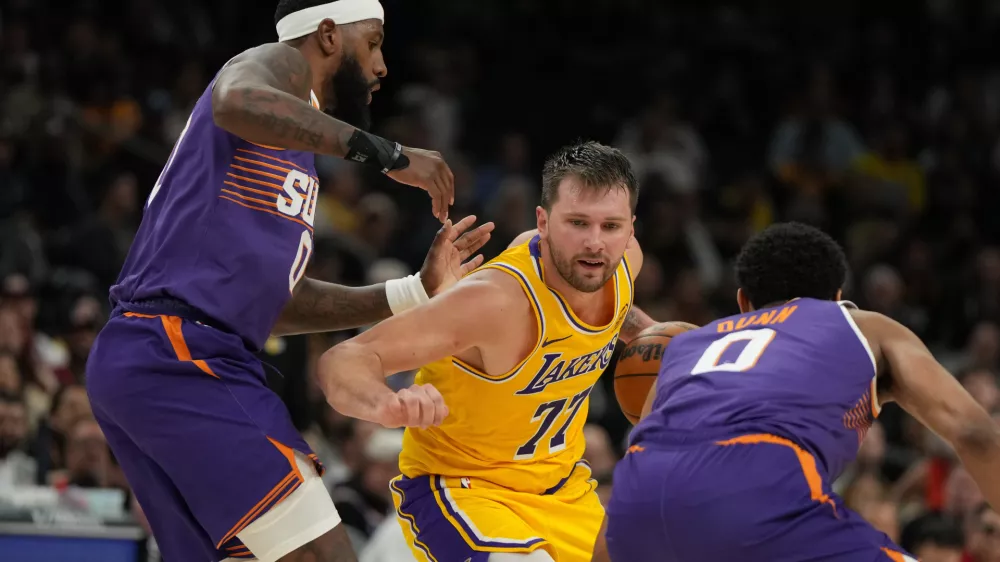 Los Angeles Lakers guard Luka Doncic drives between Phoenix Suns forward Royce O'Neale and forward Ryan Dunn (0) during the second half of an NBA basketball game, Thursday, Feb. 26, 2026, in Phoenix. (AP Photo/Rick Scuteri)