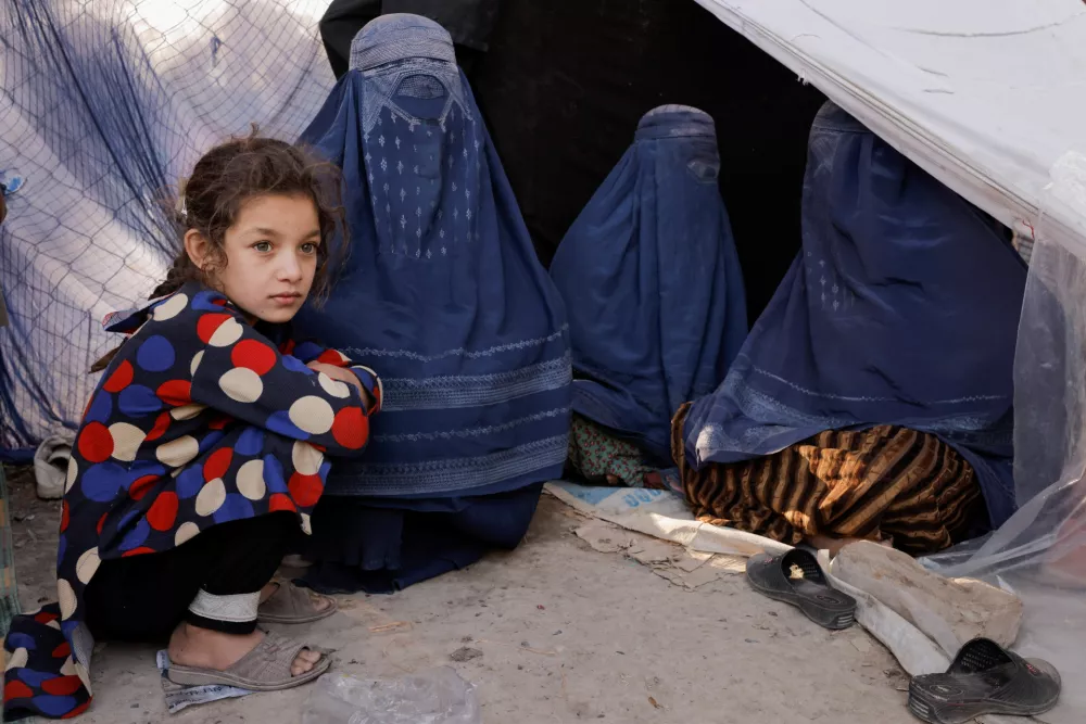 An Afghan girl and burqa-clad women, who are among displaced families fleeing the violence in their provinces, sit near a tent at a makeshift shelter at Shahr-e Naw park, in Kabul, Afghanistan October 4, 2021. REUTERS/Jorge Silva