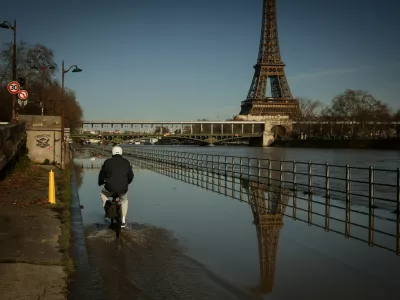 A man on a bicycle rides on the flooded banks of the Seine next to the Eiffel Tower in Paris, Wednesday Feb. 25. 2026. (AP Photo/Thomas Padilla)