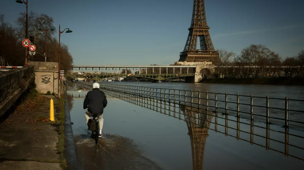 A man on a bicycle rides on the flooded banks of the Seine next to the Eiffel Tower in Paris, Wednesday Feb. 25. 2026. (AP Photo/Thomas Padilla)