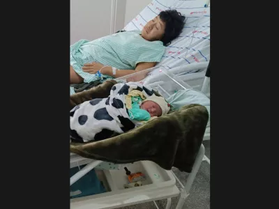 In this photo provided by Funai, Babawru Akuntsu, top, rests beside Akyp, her newborn son, at the Regional Hospital of Vilhena in Vilhena, Rondonia state, Brazil on Dec. 9, 2025, one day after the birth. (Altair Algayer/Funai via AP)