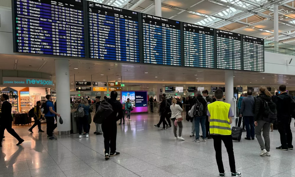 People walk past the departure board at the airport in Munich, after it was gradually resuming flights with delays expected through the day, hours after both runways were closed for the second time in less than 24 hours due to a drone sighting, in Munich, Germany, October 4, 2025. REUTERS/Ayhan Uyanik