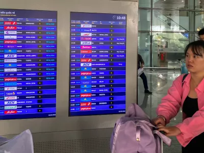 Passengers walk past a display board showing canceled flights to Dubai and Doha amid regional airspace closures at Noi Bai International Airport in Hanoi, Vietnam, March 2, 2026. Picture taken with a mobile phone. REUTERS/Thinh Nguyen