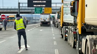 A man stands next to a line of trucks and buses on the Bosnian side of the border with Croatia, in Svilaj, Bosnia, Monday, Jan. 26, 2026, as drivers across the Balkans blocked dozens of border crossings in the region in protest over newly introduced European Union entry regulations.(AP Photo/Eldar Emric)
