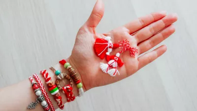 Bulgarian traditional spring decor martenitsa bracelets, holding in hand, wooden background. Baba Marta holiday, backdrop.