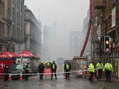 Firefighters damp down the remains of a fire which broke out in a building adjacent to Glasgow Central railway station on Sunday, in Glasgow, Scotland, Monday March 9, 2026. (Robert Perry/PA via AP)