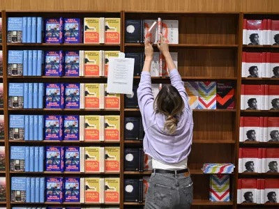 14 October 2025, Hesse, Frankfurt/Main: An employee fills the shelves with books at the S. Fischer publishers' stand at the Frankfurt Book Fair during the set-up. Photo: Arne Dedert/dpa
