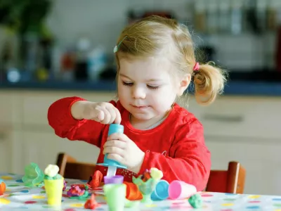 Adorable cute little toddler girl with colorful clay. Healthy baby child playing and creating toys from play dough. Small kid molding modeling clay and learning.
