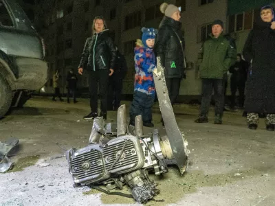 People look at fragments of a Russian drone that hit residential neighbourhood during air attack in Kharkiv, Ukraine, late Monday, March 9, 2026. (AP Photo/Andrii Marienko)