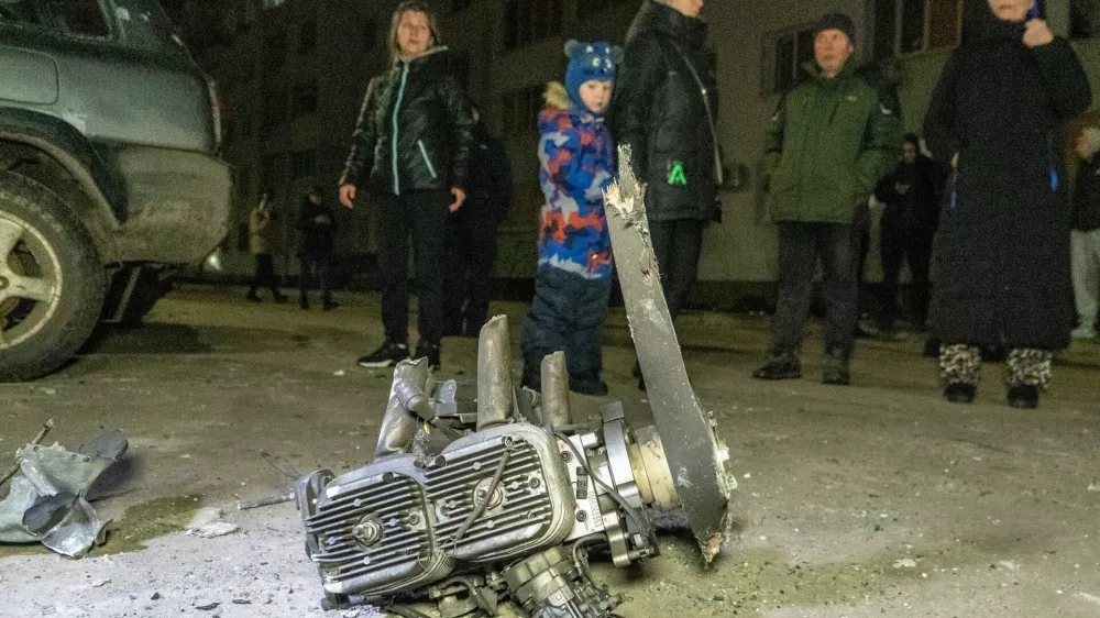 People look at fragments of a Russian drone that hit residential neighbourhood during air attack in Kharkiv, Ukraine, late Monday, March 9, 2026. (AP Photo/Andrii Marienko)