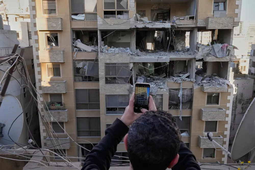 A man takes pictures of destroyed apartments that were hit by Israeli airstrikes in Beirut, Lebanon, Wednesday, March 11, 2026. (AP Photo/Hussein Malla)