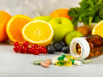 Vitamins and supplements. Variety of vitamin tablets in a jar on a texture background.Multivitamins with fresh and healthy fruits.Food supplements. Flat lay. Space for text.Copy space