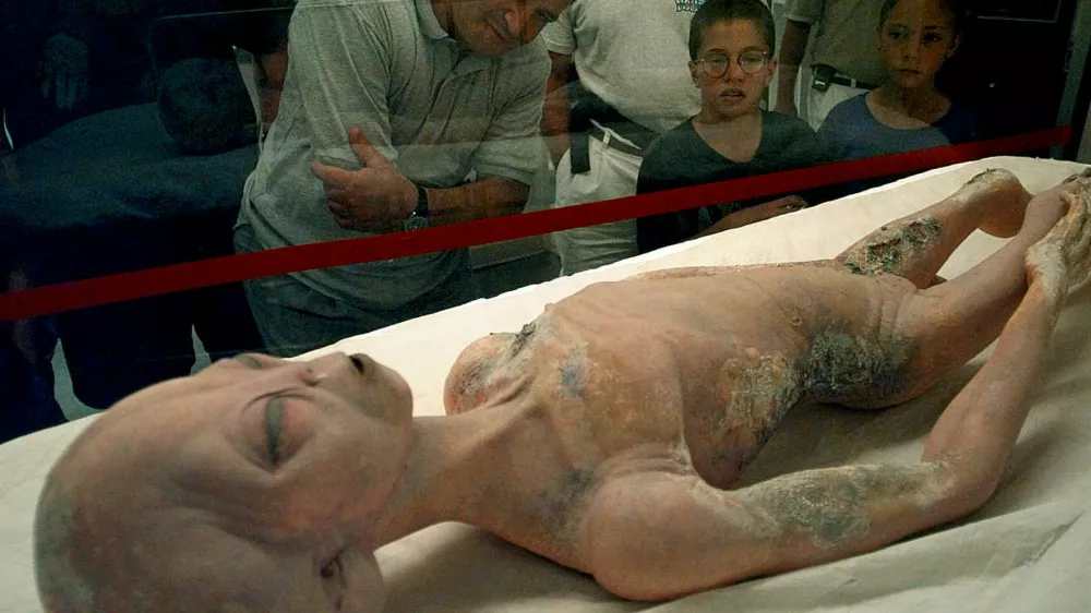 Visitors to the International UFO Museum in Roswell, New Mexico examine a glass-encased alien prop used in the movie "Roswell" Wednesday, July 2, 1997. Over 2,000 visitors walked through the museum Monday as tourists began to pour into town for the 50th anniversary of the Roswell incident. (AP Photo/Susan Sterner)