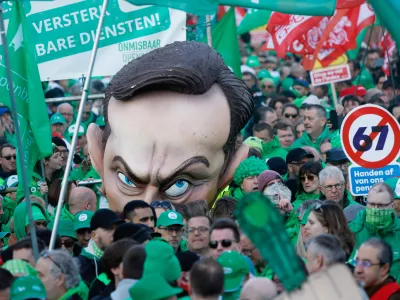 Protestors wheel a giant puppet head depicting Belgium's Prime Minister Bart De Wever and hold signs which read "hands off our pensions" as they demonstrate during general strike actions in Brussels, Thursday, March 12, 2026. (AP Photo/Geert Vanden Wijngaert)