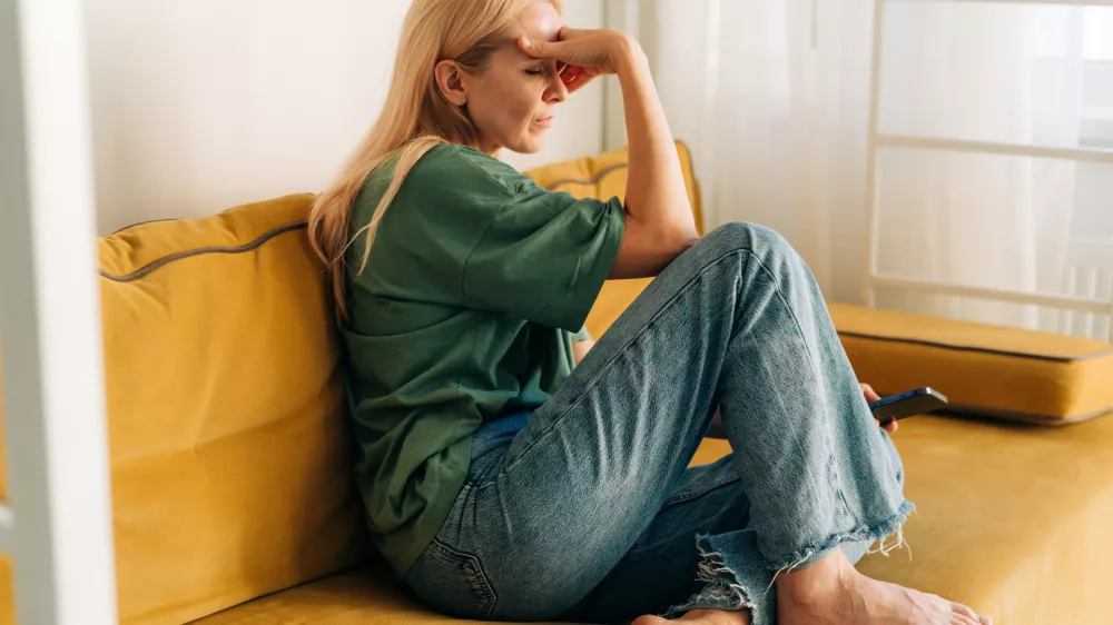 Depressed sad middle aged woman sitting on sofa at home. / Foto: Ilona Titova