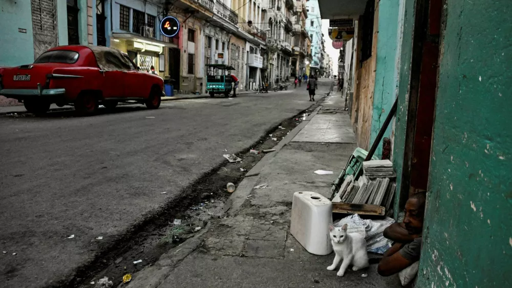 A man and his cat sit at the door of their home as Cuba's President Miguel Diaz-Canel announces on state television that the country has opened talks with the U.S. government amid a severe economic crisis and as the Communist government has come under increasing pressure from U.S. President Donald Trump, in Havana, Cuba, March 13, 2026. REUTERS/Norlys Perez   TPX IMAGES OF THE DAY