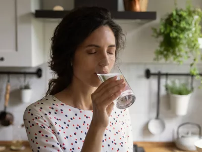Pure pleasure. Thirsty millennial female drink swallow cool clear mineral aqua from glass at home kitchen feel delight. Young woman enjoy crystal filtered potable water with closed eyes relieve stress / Foto: Fizkes Getty Images