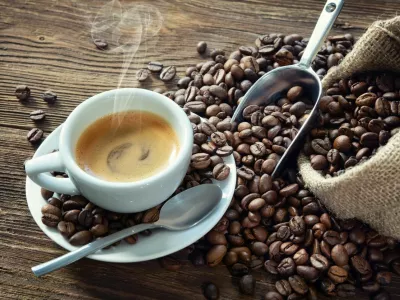Cup of espresso with coffee beans, bag, scoop and steam on rustic wooden background / Foto: Alexraths