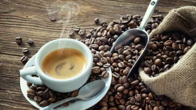 Cup of espresso with coffee beans, bag, scoop and steam on rustic wooden background / Foto: Alexraths