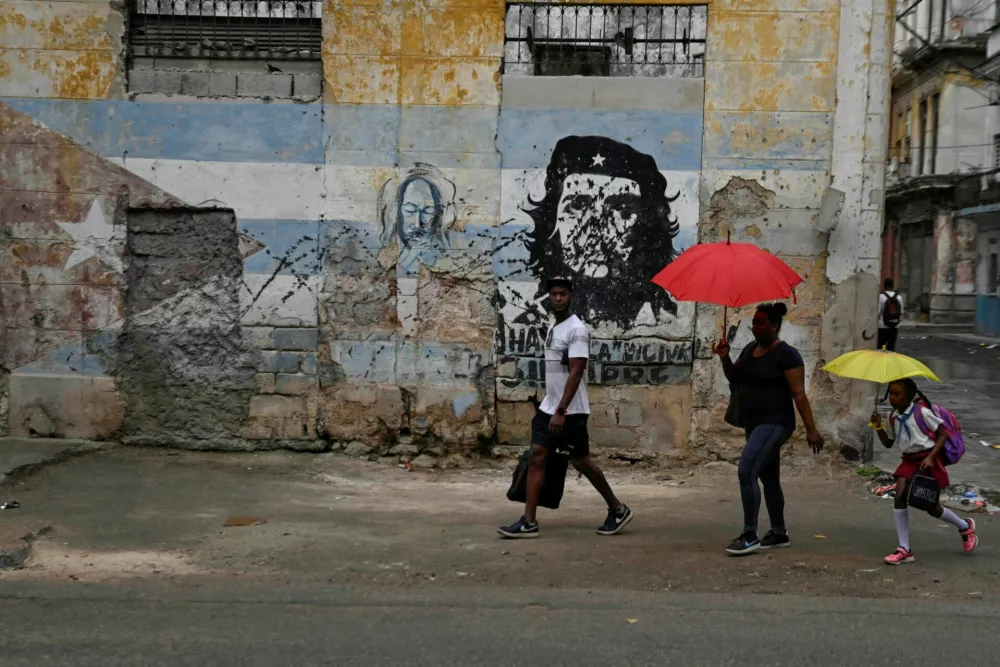 People walk past an image of late revolutionary Ernesto "Che" Guevara painted on a wall, as Cuba reconnected its electrical grid across much of the island, according to the Energy and Mines Ministry, following a nationwide blackout that left about 10 million people without electricity, in Havana, Cuba, March 17, 2026. REUTERS/Norlys Perez