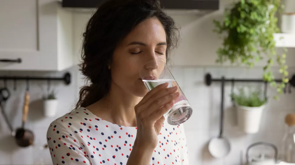 Pure pleasure. Thirsty millennial female drink swallow cool clear mineral aqua from glass at home kitchen feel delight. Young woman enjoy crystal filtered potable water with closed eyes relieve stress