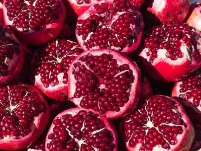 a lot of ripe red pomegranates with a cut off top, close-up background, space for an inscription. High quality photo / Foto: Denys Popov