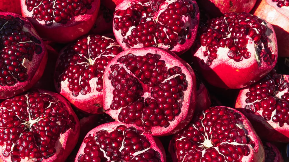a lot of ripe red pomegranates with a cut off top, close-up background, space for an inscription. High quality photo / Foto: Denys Popov