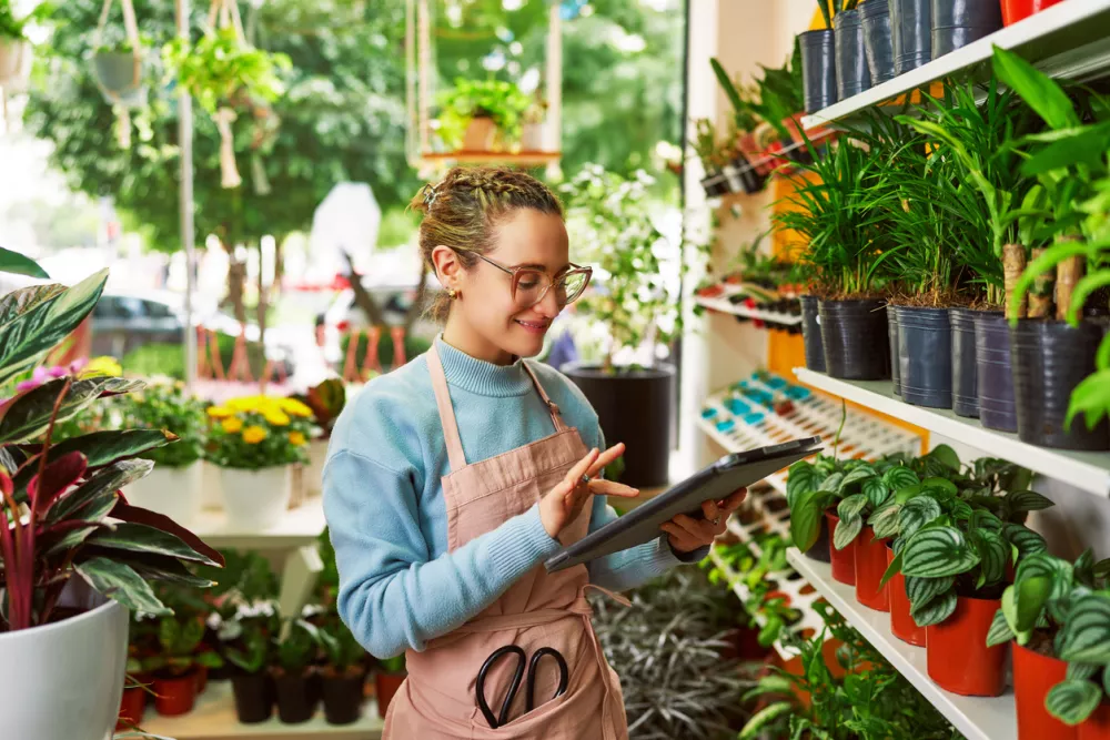 caucasian female worker seller plant shop holding a tablet / Foto: Getty Images Oscar Gutierrez Zozulia