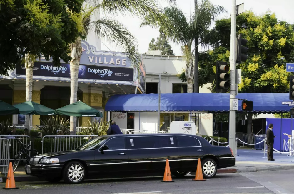 Los Angeles, California, USA - September 17, 2011: Limousine parked in front of the Fox Village Theatre during the premiere of the film \"Dolphin Tale\", with a security guard checking the entrance and people at the outdoor tables of the adjacent Starbucks Coffee shop. / Foto: Paoloscarlata