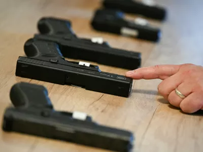24 October 2025, Hesse, Wiesbaden: During a press conference at the Federal Criminal Police Office (BKA), a BKA forensic technician points to a converted alarm firearm, while an original alarm firearm can be seen behind it. In the foreground is a firearm manufactured by Glock. The Federal Ministry of the Interior and the BKA present the Federal Situation Reports on Narcotics and Organized Crime 2024 in Wiesbaden. Photo: Arne Dedert/dpa,Image: 1047799211, License: Rights-managed, Restrictions: GERMANY OUT, Model Release: no