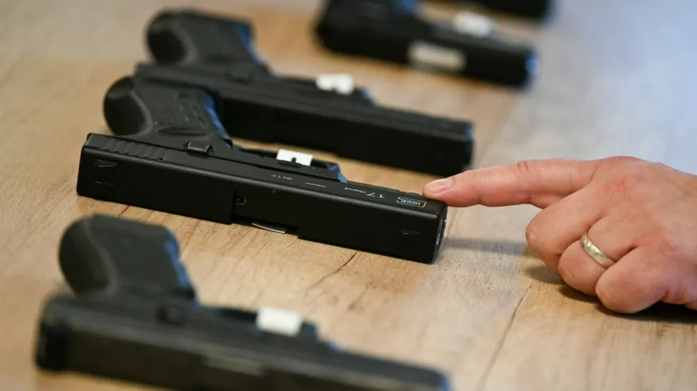 24 October 2025, Hesse, Wiesbaden: During a press conference at the Federal Criminal Police Office (BKA), a BKA forensic technician points to a converted alarm firearm, while an original alarm firearm can be seen behind it. In the foreground is a firearm manufactured by Glock. The Federal Ministry of the Interior and the BKA present the Federal Situation Reports on Narcotics and Organized Crime 2024 in Wiesbaden. Photo: Arne Dedert/dpa,Image: 1047799211, License: Rights-managed, Restrictions: GERMANY OUT, Model Release: no