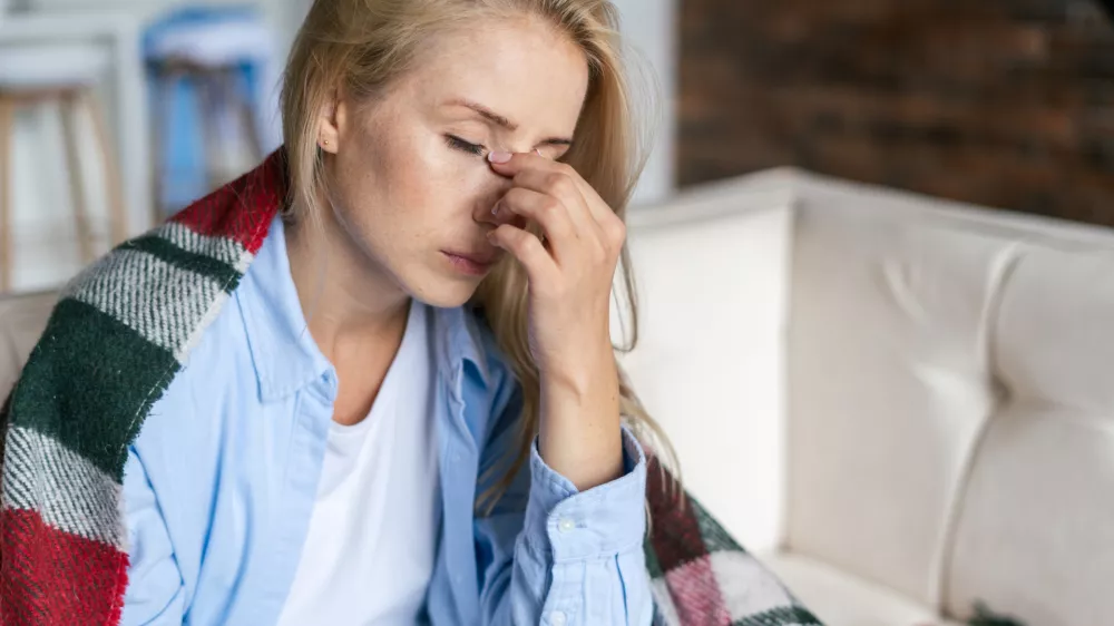 Fatigue and upset woman touching nose bridge feeling eye strain or headache, trying to relieve pain. Sick and exhausted female spending day at home. Depressed lady feeling weary dizzy