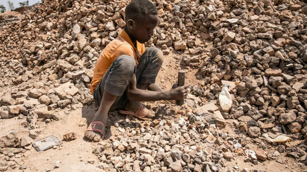 Children work in an aggregate mining site, Kolwezi. As a climate emergency approaches, industries across the world slowly begin to adapt and change. Demand soars for materials needed for renewable technologies, with cobalt and copper more essential than ever for use in electric vehicle batteries and other cutting-edge applications. Around two thirds of Earth's deposits of the ores that contain cobalt, as well as vast reserves of copper, are found in the dusty southern provinces of the Democratic Republic of Congo. With a renewed interest from the global community, billions of dollars flow in and out of Congo. Multinational companies vie for rights to mineral deposits and Congolese politicians create a fruitful niche for themselves in the sale of contracts and site access around the mining town of Kolwezi. Little of this wealth comes to those who live and work here, as communities find themselves exploited, poisoned and excluded from the riches of the green minerals of the electric future.,Image: 804607234, License: Rights-managed, Restrictions:, Model Release: no