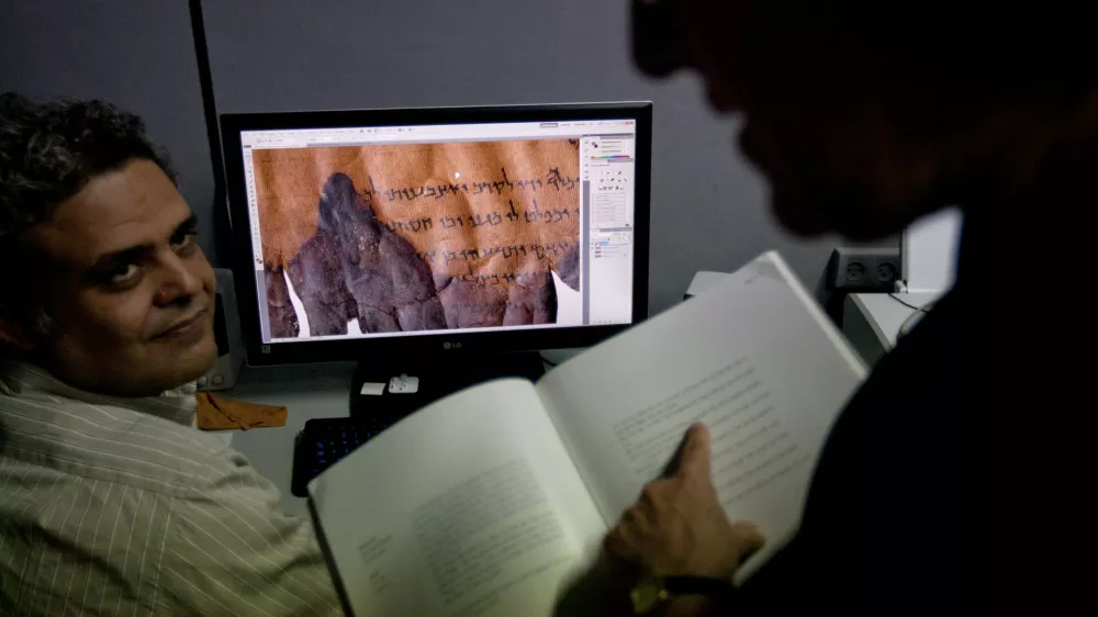 Photographer Yair Medina, left, shows Pnina Shor, right, curator and Head of Dead Sea Scrolls Project at the Israel Antiquities Authority, IAA, scanned fragments of the Dead Sea Scrolls on a computer screen, at the IAA offices at the Israel Museum in Jerusalem, Monday, Sept. 26, 2011. Two thousand years after they were written and decades after they were found in desert caves, some of the world-famous Dead Sea Scrolls are available online. Israel's national museum and the international web giant Google are behind the project, which saw five scrolls go online Monday. (AP Photo/Sebastian Scheiner)