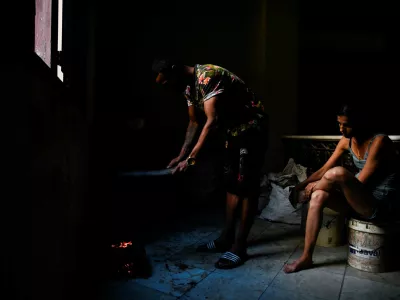 Jesus Rodriguez lights charcoal for cooking while his wife, Yaliet Iglesias, sits nearby as Cuba's national electric grid collapsed for the second time in a week amid the U.S.-imposed oil blockade, according to officials, as the communist government struggles to keep the lights on for about 10 million people with decrepit infrastructure, in Havana, Cuba, March 21, 2026. REUTERS/Norlys Perez