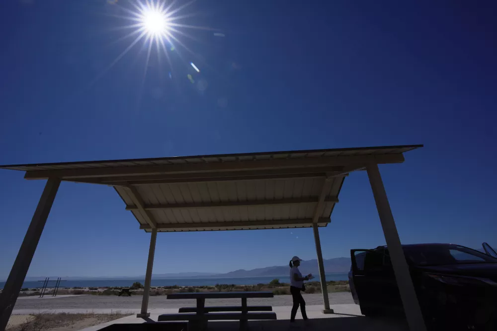 A woman packs up after resting in a shaded area alongside the Salton Sea as a record-breaking winter heat wave continues across the Southwest, Thursday, March 19, 2026, near North Shore, Calif. (AP Photo/Gregory Bull)