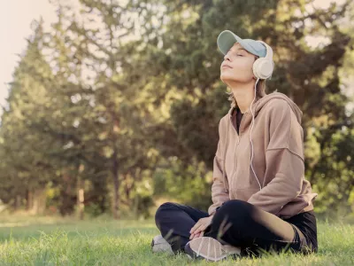 Woman listening to music with headphones in the nature / Foto: Seb_ra Getty Images