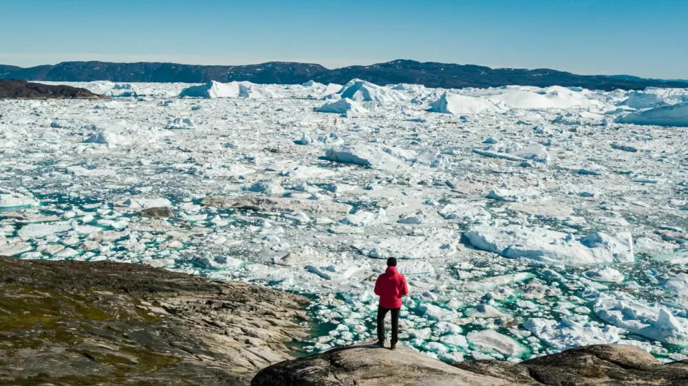 Travel in arctic landscape nature with icebergs - Greenland tourist man explorer - tourist person looking at amazing view of Greenland icefjord - aerial drone image. Man by ice and iceberg, Ilulissat. / Foto: Maridav