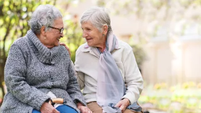 Two elderly women sitting on bench in park smiling happy life long friends enjoying retirement