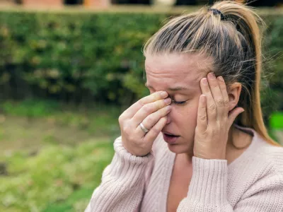 Woman with headache. Seasonal allergies and health problems. Sinus ache causing very paintful headache. Unhealthy woman in pain. Sharp strong sore. Flu cold or allergy symptom. Sinus pain, sinusitis.