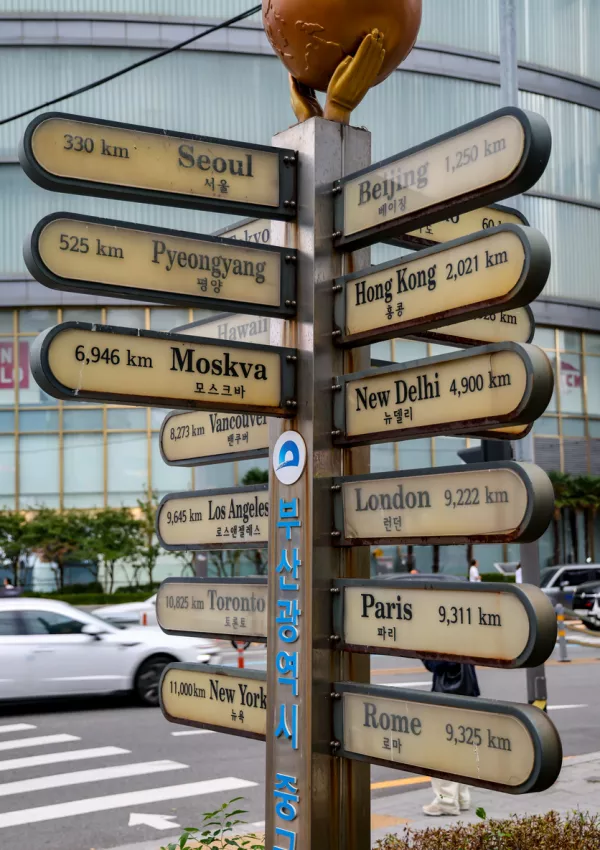 Metal signpost indicating distances to international cities in Busan, South Korea, on a city street / Foto: Cineman69